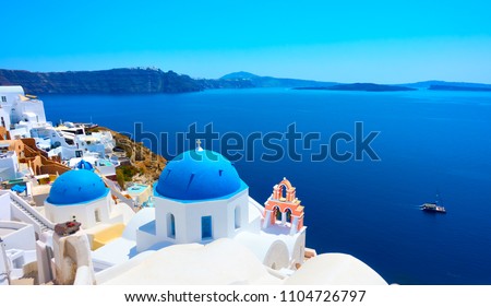 Panoramic view with Greek orthodox church with blue domes and sea in Oia in Santorini, Greece
