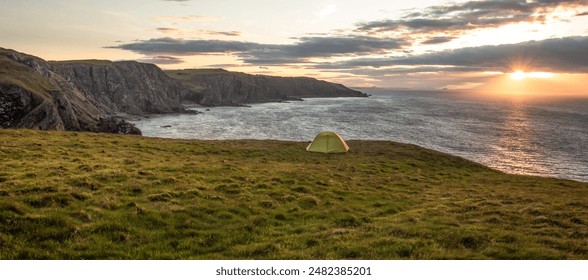 Panoramic view of a green camping tent on a grassy cliff by the sea at sunset at St. Abbs Head, east coast of Scotland - Powered by Shutterstock