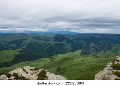 Panoramic view of green mountains and hills from the Bermamyt plateau in Karachay-Cherkessia in Russia on a cloudy summer day and copy space in a hazy haze on the horizon - Shutterstock ID 2222933883