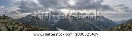 Panoramic view to the Grimsel lake in Swiss Alps with dramatic sun rays breaking through clouds