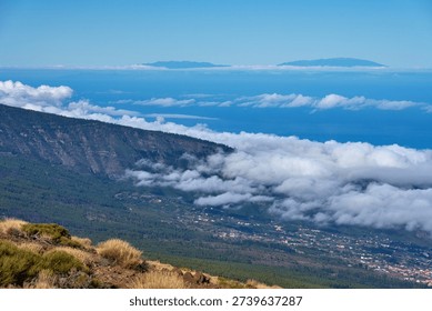 Panoramic view from high elevation above Teide National Park looking down over Puerto de la Cruz, pine forest, and the Atlantic Ocean with a band of clouds on the horizon