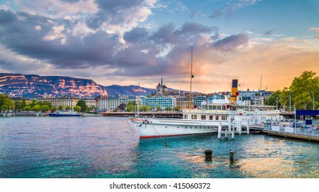 Panoramic view of the historic city center of Geneva with traditional paddle steamer boat on Lake Geneva in beautiful golden evening light at sunset with blue sky and clouds in summer, Switzerland