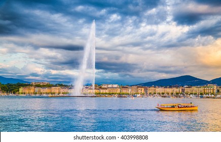 Panoramic view of historic Geneva skyline with famous Jet d'Eau fountain at harbor district in beautiful evening light at sunset with blue sky and clouds in summer, Canton of Geneva, Switzerland