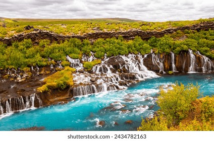 Panoramic view of Hraunfossar near Borgarfjörður (Iceland), a series of waterfalls and cascades formed by rivulets streaming out of a lava field. Major attraction with turquoise water in wild scenery. - Powered by Shutterstock