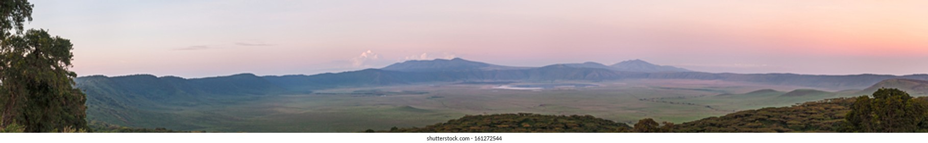 Panoramic view of huge Ngorongoro caldera (extinct volcano crater) against sunrise glow background. Great Rift Valley, Tanzania, East Africa.  