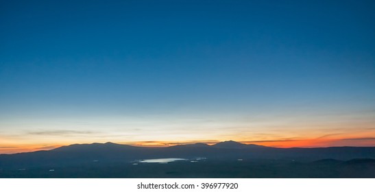Panoramic view of huge Ngorongoro caldera (extinct volcano crater) with lake against evening glow background at dusk. Great Rift Valley, Tanzania, East Africa.
