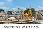 A panoramic view of the iconic Kashi Vishwanath Temple in Varanasi, showcasing the intricately designed golden spires under a clear blue sky. A perfect blend of heritage and spirituality.