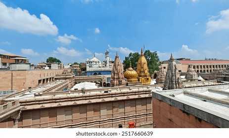 A panoramic view of the iconic Kashi Vishwanath Temple in Varanasi, showcasing the intricately designed golden spires under a clear blue sky. A perfect blend of heritage and spirituality. - Powered by Shutterstock