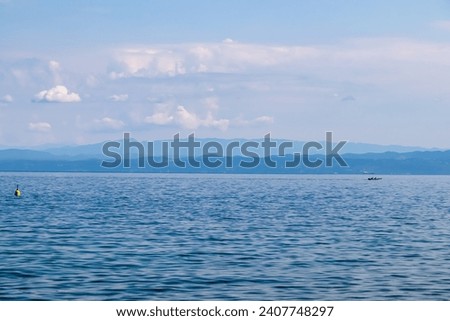 Panoramic view of idyllic coastline seen from Gulf of Piran, Adriatic Mediterranean Sea, Slovenia, Europe. Summer seaside vacation. Distant mountain ranges of Julian Alps. Ships floating in calm water