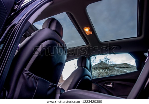 Panoramic view\
inside car - double sunroof hatch with tinted glass. Sliding\
panoramic sunroof and luxurious leather seats. Close up photo with\
bright blue sky seen through\
sunroof.