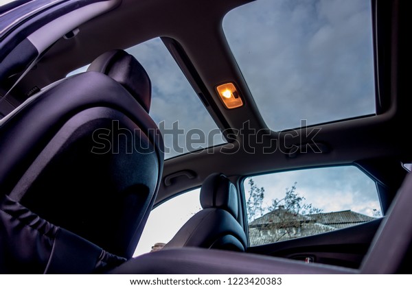 Panoramic view\
inside car - double sunroof hatch with tinted glass. Sliding\
panoramic sunroof and luxurious leather seats. Close up photo with\
bright blue sky seen through\
sunroof.