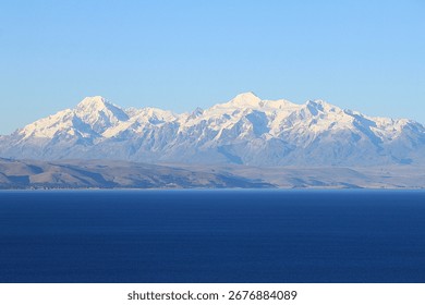 Panoramic view from Isla del Sol (Island of the sun) over seemingly endless Lake Titikaka in Bolivia to andean mountain ridge of Cordillera Real with snow covereded peaks and glaciers.