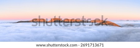 Panoramic view of Lake District cloud inversion with Scafell mountain range at sunrise.