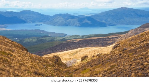 Panoramic view of Lake Taupo in New Zealand's volcanic plateau. Emerald waters cradle lush greenery, a vibrant blue sky dotted with cotton-candys completes this picture of serene beauty. - Powered by Shutterstock