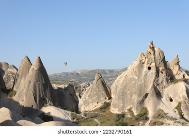 Panoramic view of landscape of Cappadocia and valley with rocky mountains and caves. One hot air balloon over fairy chimneys in Cappadocia, Goreme National Park, Turkey. - Shutterstock ID 2232790161