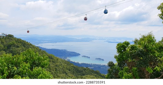 Panoramic view of Langkawi Island, Malaysia with cable car trip for tourist to enjoy beautiful scenery and experience. Overlooking aerial view of blue sky, green trees, sea and mountain. - Powered by Shutterstock