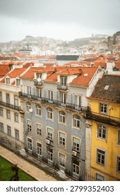 Panoramic view of Lisbon rooftops and steep streets in Portugal. Scenic urban landscape featuring historic architecture and dense city layout under cloudy skies.