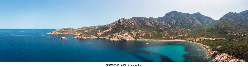 Panoramic View Of A Lone Catamaran Moored In A Large Rocky Cove On The West Coast Of Corsica On The Turquoise Mediterranean Sea