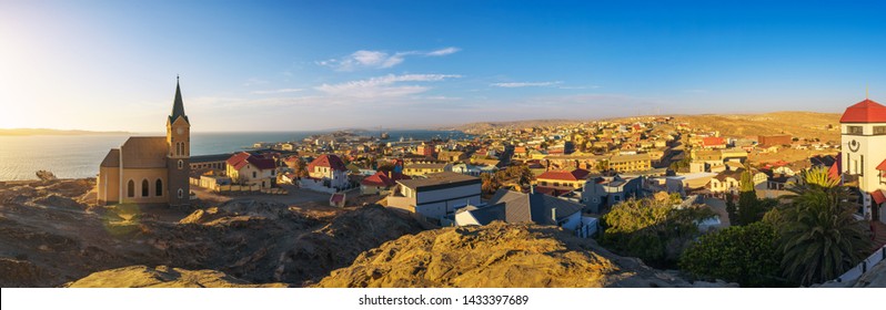 Panoramic view of Luderitz in Namibia at sunset with lutheran church called Felsenkirche and atlantic ocean in the background.