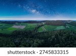 Panoramic view of lush fields and forests under a starlit sky at twilight in the countryside
