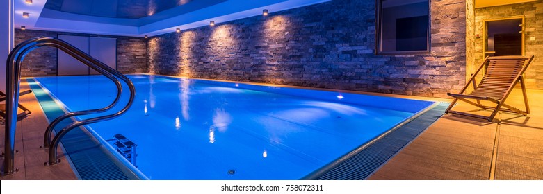 Panoramic View Of Luxurious Swimming Pool With Brick Wall And Deck Chair