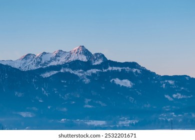 Panoramic view of majestic snow-capped mountain peak Mittagskogel (Kepa) in Karawanks seen from Rosental, Carinthia, Austria. Tranquil alpine landscape. Peaceful scene in Austrian Alps in winter - Powered by Shutterstock