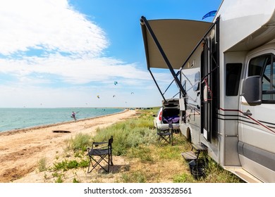 Panoramic view of many surf board kite riders on sand beach watersport spot on bright sunny day against rv camper van vehicle at sea ocean coast at surfing camp. Fun adventure travel sport acitivity - Powered by Shutterstock