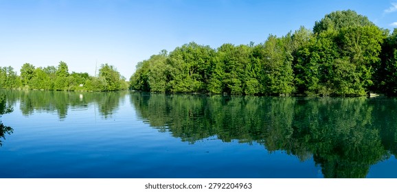 Panoramic view of the Marne river and trees reflecting on the water along the towpath with sunny blue sky