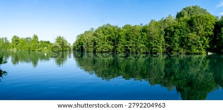 Panoramic view of the Marne river and trees reflecting on the water along the towpath with sunny blue sky