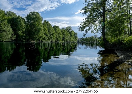 Panoramic view of the Marne river and trees reflecting on the water along the towpath with sunny blue sky