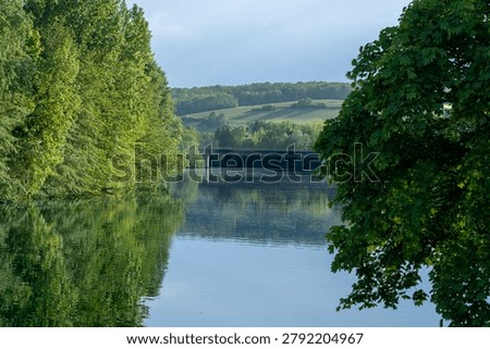 Panoramic view of the Marne river and trees reflecting on the water along the towpath with sunny blue sky