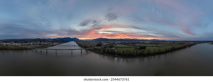 Panoramic view of Mission, British Columbia at sunset, featuring the Fraser River, lush fields, and distant mountains under a colorful sky. Captures the serene beauty of the Canadian landscape. - Powered by Shutterstock