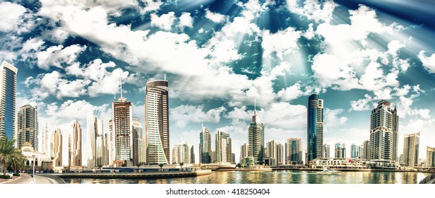 Panoramic view with modern skyscrapers and water pier of Dubai Marina at sunset, UAE.