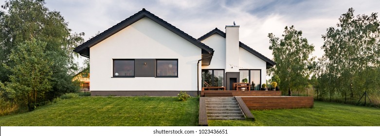 Panoramasicht auf das moderne Weiße Haus mit Holzterrasse und grünem Rasen