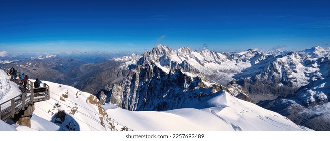Panoramic view of Mont Blanc massif snow mountain with tiny snow climber or hiker at the ridge of the mountain - Shutterstock ID 2257693489
