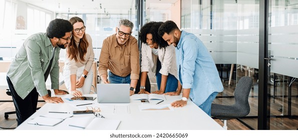 A panoramic view of a motivated team intensely focused on a computer screen, capturing the essence of a strategic work session in a contemporary, light-filled office. Diverse work group brainstorming - Powered by Shutterstock