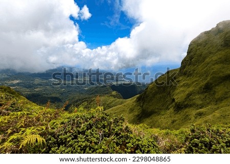 Panoramic view from Mount Pelée hiking track on the tropical island Martinique, France. Lush volcanic mountain vegetation in wide landscape. Saint Pierre village and Caribbean sea in the background.