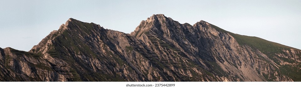 panoramic view of a mountain range with green slopes  in summer