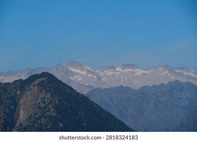 Panoramic view of mountain range with snow-capped peaks under a clear blue sky