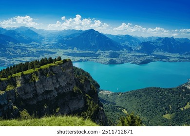 A panoramic view of a mountain range with a turquoise lake in the foreground under a clear blue sky