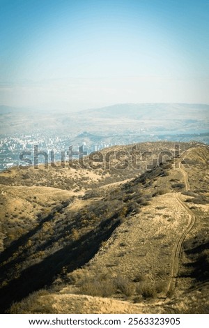 Panoramic view of a mountain ridge between Tsodoreti and Lisi Lake with a suburban district of Tbilisi in the background. A blend of natural textures and urban landscapes in autumn light