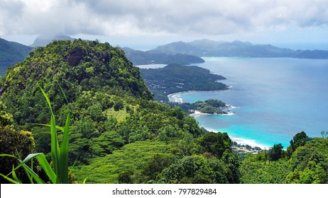 A Panoramic View of nature on the Seychelles with green forests, fresh plants, towering hills, white beaches, turquoise blue water under cloudy sky - Shutterstock ID 797829484