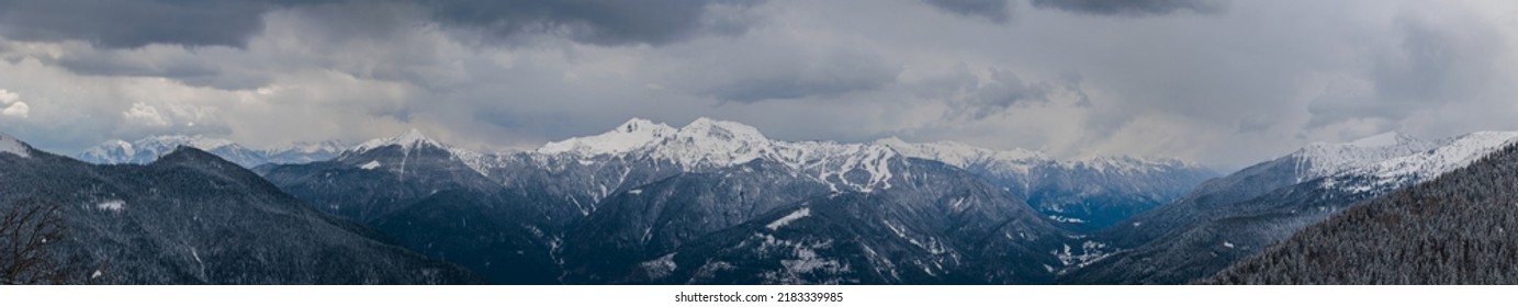 panoramic view, near 180 degrees, of a beautiful mountain environment in the afternoon at the end of winter season. mountain ranges covered in snow. dark snowy clouds dominating the landscape - Shutterstock ID 2183339985
