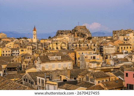 Panoramic view of the Old Town of Corfu, Greece, with traditional Venetian architecture, tiled rooftops, narrow streets, and the Old Fortress in the background during a clear summer evening.