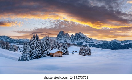 Panoramic view on Alpe di Siusi meadow with cozy wooden log cabins and sunset sky. Snowy hills with orange larch and first snow in winter season. Seiser Alm, Dolomites, Italy. Landscape photography - Powered by Shutterstock