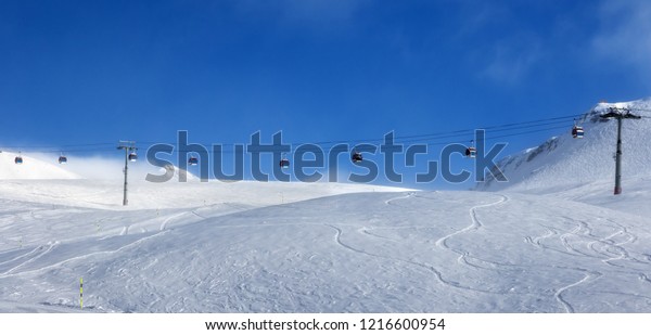 Panoramic view on gondola lift and off-piste ski\
slope in fog at nice sunny evening. Caucasus Mountains in winter,\
Georgia, region\
Gudauri.