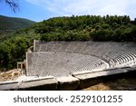 Panoramic view on a sunny summer day over the Ancient Theatre of Epidaurus in Greece, dedicated to the ancient Greek God of medicine, Asclepius. Holidays and sightseeing in Greece