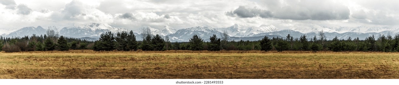 Panoramic view on Tatra Mountains, Poland seen from further. Snow-covered peaks of the rocky mountains and cloudy sky in the time of early spring. Natural background. - Powered by Shutterstock