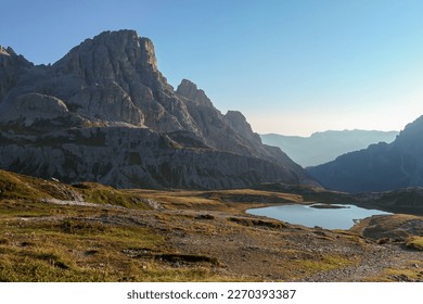 A panoramic view on a vast valley in Italian Dolomites during early morning hours. The valley is surrounded with high mountains from each side. Small lake in the middle. Remote and isolated place. - Powered by Shutterstock