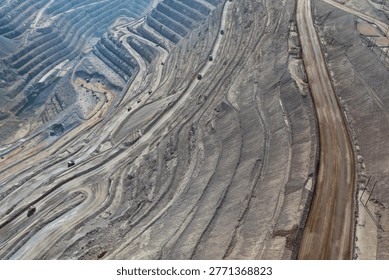 Panoramic view of an open-pit mine with multiple dump trucks transporting minerals